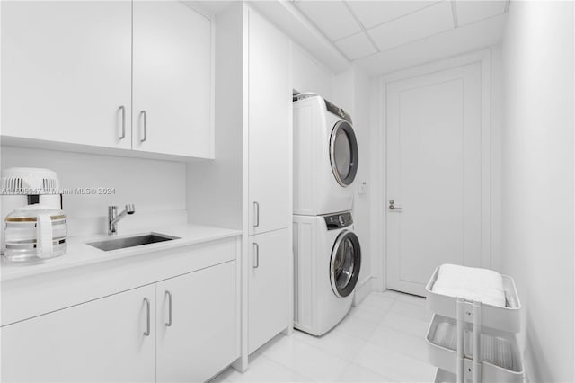 clothes washing area with cabinets, stacked washing maching and dryer, and sink