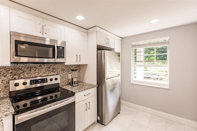 kitchen featuring light stone counters, white cabinetry, stainless steel appliances, and tasteful backsplash