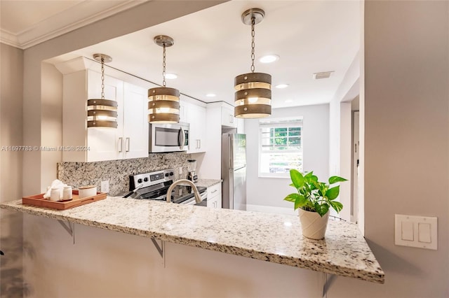 kitchen featuring kitchen peninsula, appliances with stainless steel finishes, decorative light fixtures, white cabinets, and a breakfast bar area