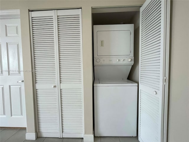 laundry room with light tile patterned floors and stacked washer and dryer