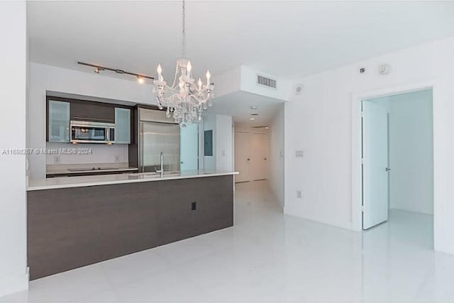 kitchen with sink, hanging light fixtures, a notable chandelier, dark brown cabinetry, and stainless steel appliances