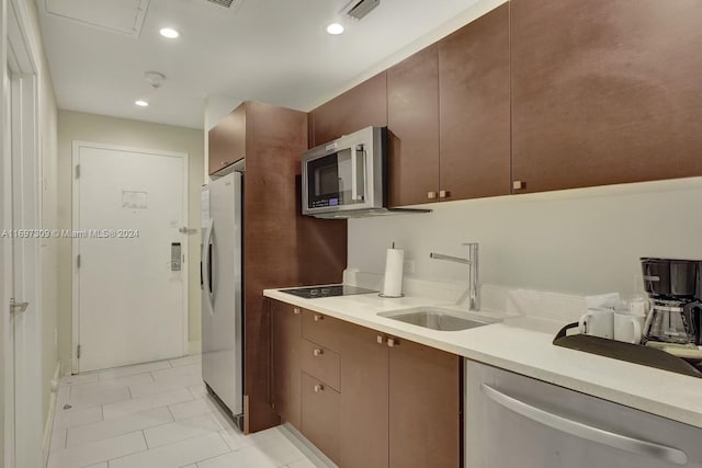 kitchen with dark brown cabinets, light tile patterned flooring, sink, and appliances with stainless steel finishes