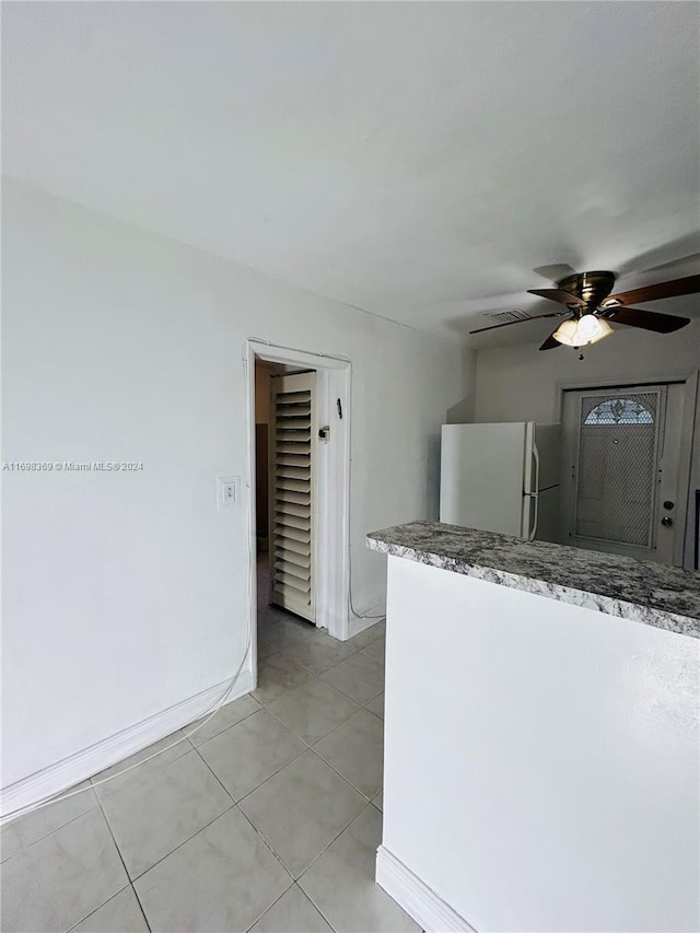 kitchen with light tile patterned floors, white fridge, and ceiling fan