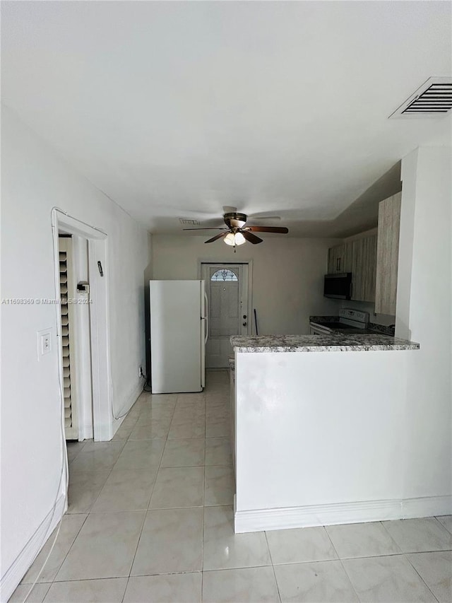 kitchen featuring ceiling fan, light stone counters, kitchen peninsula, white appliances, and light tile patterned flooring