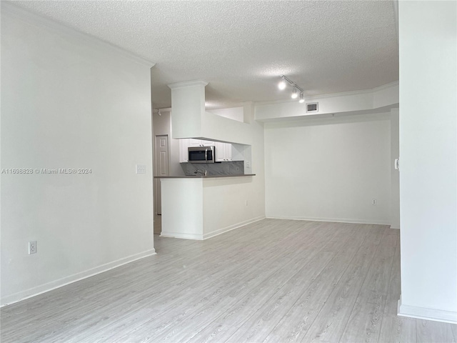 unfurnished living room featuring a textured ceiling, light wood-type flooring, and rail lighting