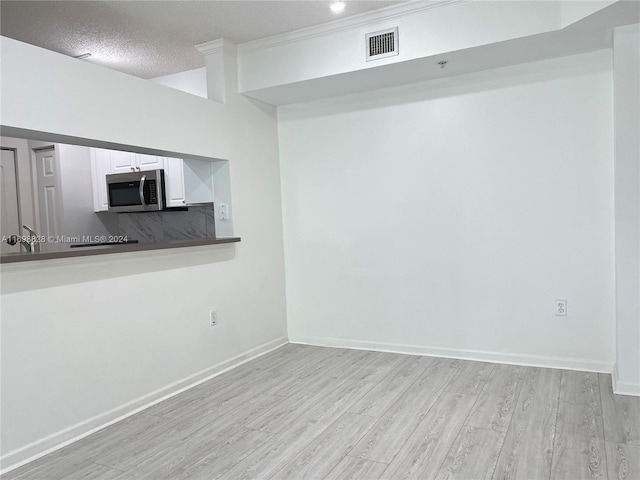 unfurnished living room with light hardwood / wood-style floors and a textured ceiling