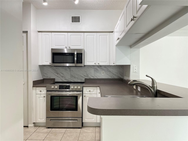 kitchen featuring decorative backsplash, light tile patterned floors, a textured ceiling, white cabinetry, and stainless steel appliances