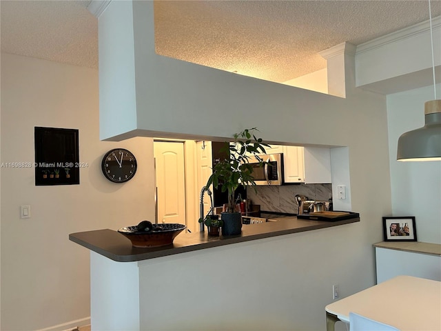 kitchen with kitchen peninsula, white cabinetry, a textured ceiling, and decorative backsplash