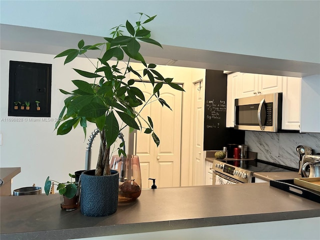 kitchen featuring backsplash, white cabinetry, and stainless steel appliances