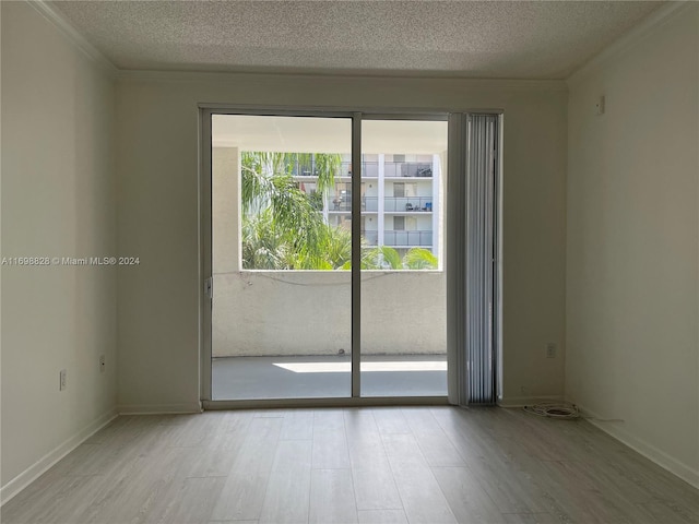 empty room featuring light hardwood / wood-style flooring, a textured ceiling, and ornamental molding