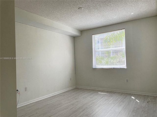 spare room with light hardwood / wood-style flooring and a textured ceiling