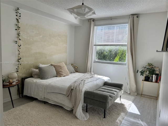 bedroom featuring light hardwood / wood-style floors and a textured ceiling