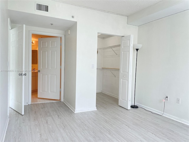 unfurnished bedroom with a closet, a textured ceiling, and light hardwood / wood-style flooring