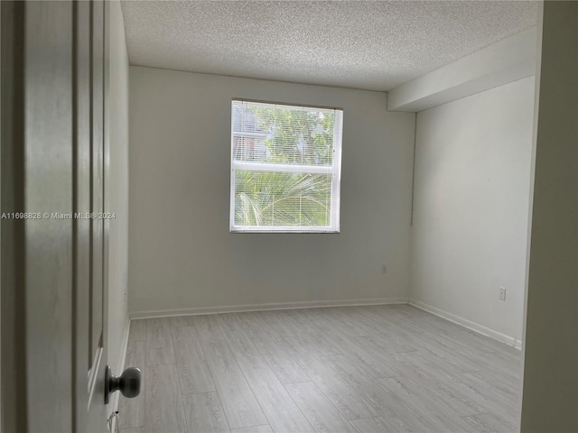 spare room with light wood-type flooring and a textured ceiling