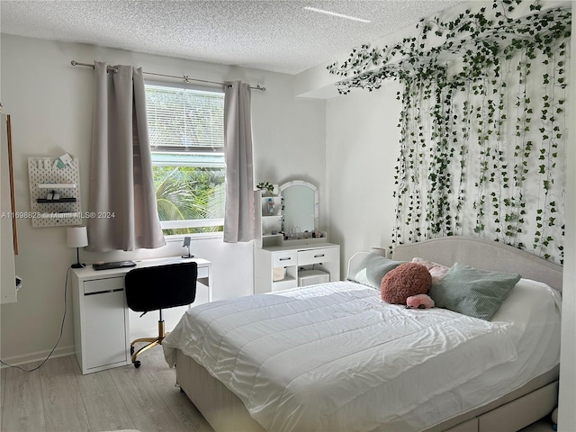 bedroom featuring light hardwood / wood-style floors and a textured ceiling