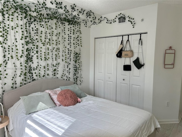 bedroom with a closet, a textured ceiling, and hardwood / wood-style flooring