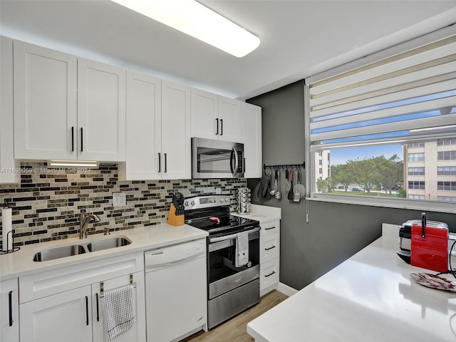 kitchen with tasteful backsplash, white cabinetry, sink, and stainless steel appliances