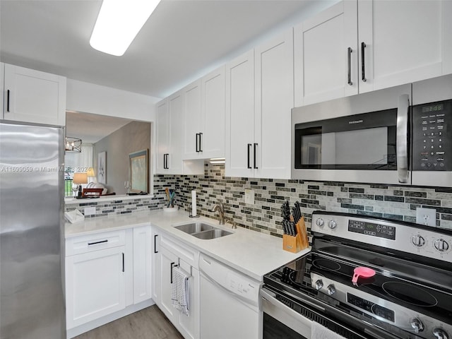 kitchen with tasteful backsplash, sink, white cabinets, and stainless steel appliances