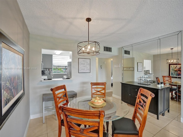 dining area with light tile patterned flooring, a textured ceiling, and an inviting chandelier