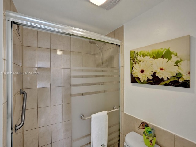 bathroom featuring a shower with shower door and toilet