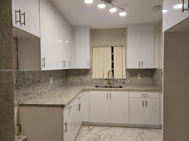 kitchen featuring decorative backsplash, sink, white cabinets, and light stone counters