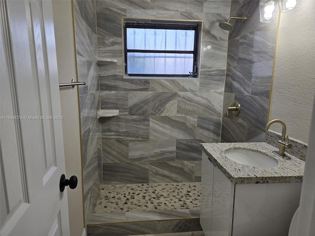 bathroom with tiled shower and vanity