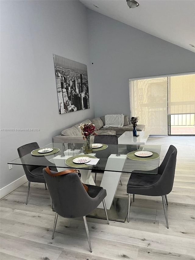 dining space featuring light wood-type flooring and high vaulted ceiling