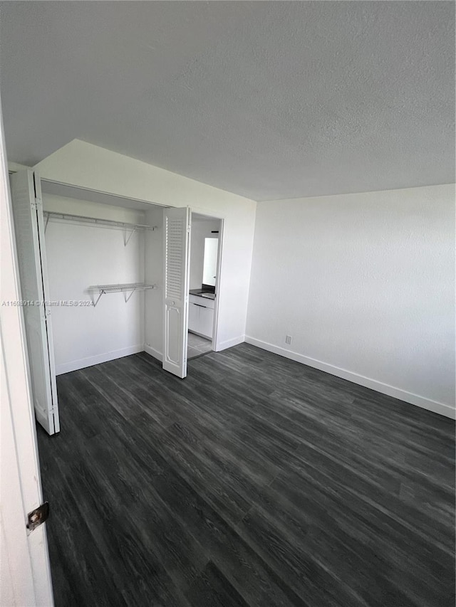 unfurnished bedroom featuring dark hardwood / wood-style floors, a textured ceiling, and a closet