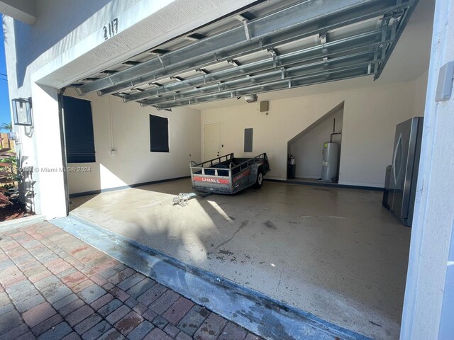 garage with electric panel, stainless steel fridge, and electric water heater