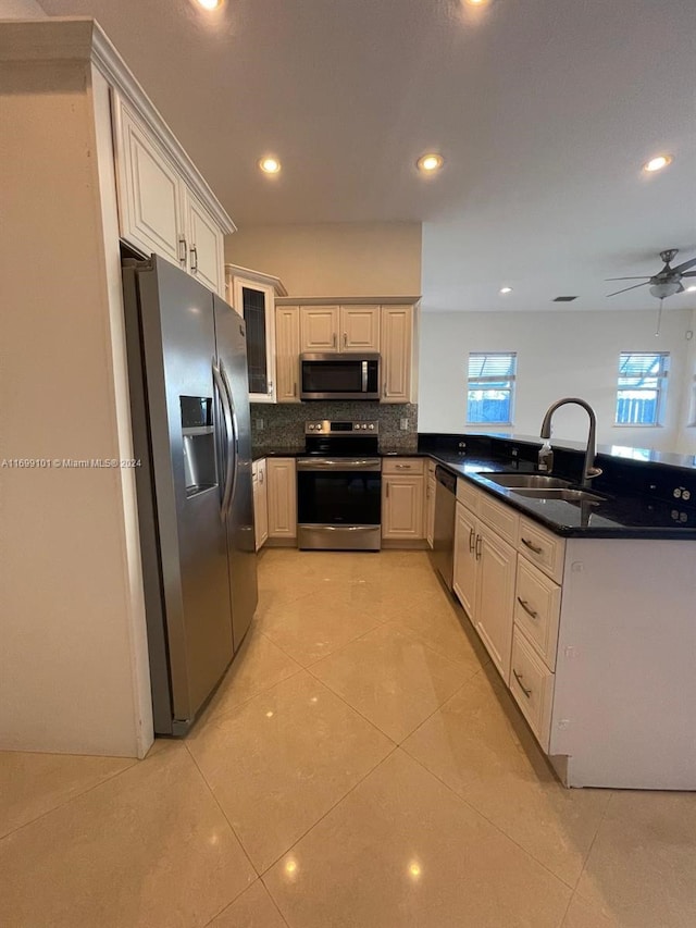 kitchen with ceiling fan, sink, kitchen peninsula, light tile patterned floors, and appliances with stainless steel finishes