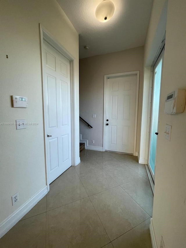 hallway with a textured ceiling and light tile patterned flooring