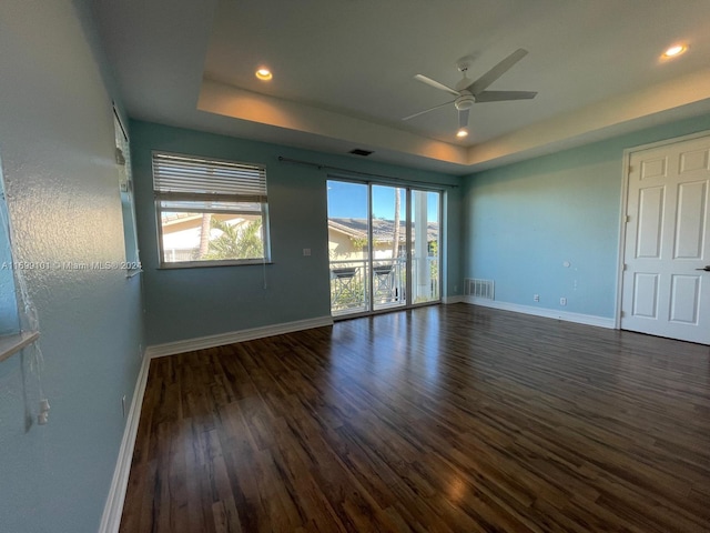 spare room with dark hardwood / wood-style floors, ceiling fan, and a tray ceiling