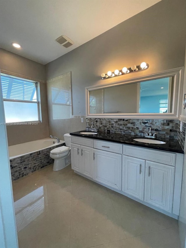 bathroom with tasteful backsplash, tile patterned floors, vanity, toilet, and a bathing tub