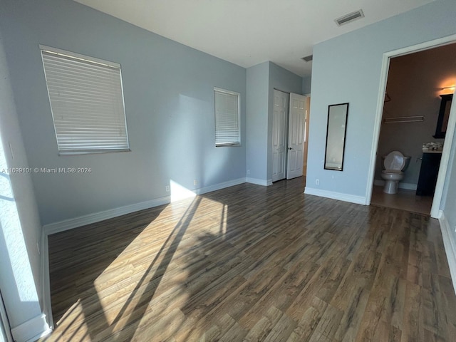 unfurnished bedroom featuring dark hardwood / wood-style floors and ensuite bathroom