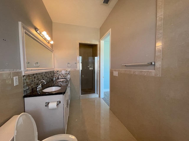 bathroom with vanity, a shower with shower door, tile walls, and toilet