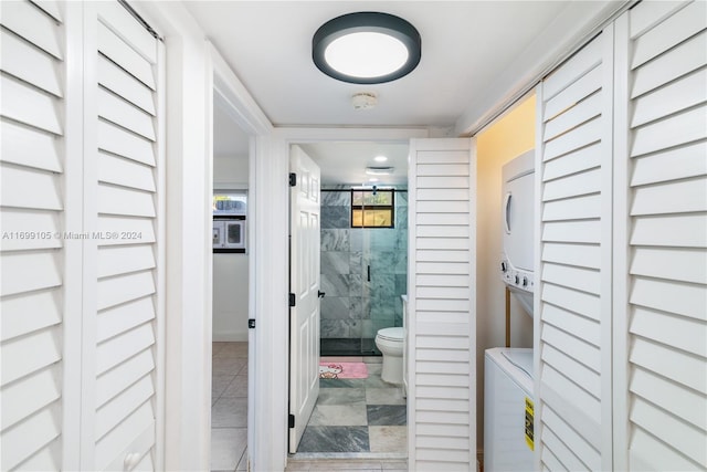 bathroom with tile patterned flooring, toilet, an enclosed shower, and stacked washing maching and dryer