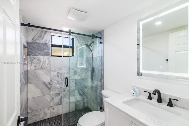 bathroom featuring a shower with door, vanity, and toilet