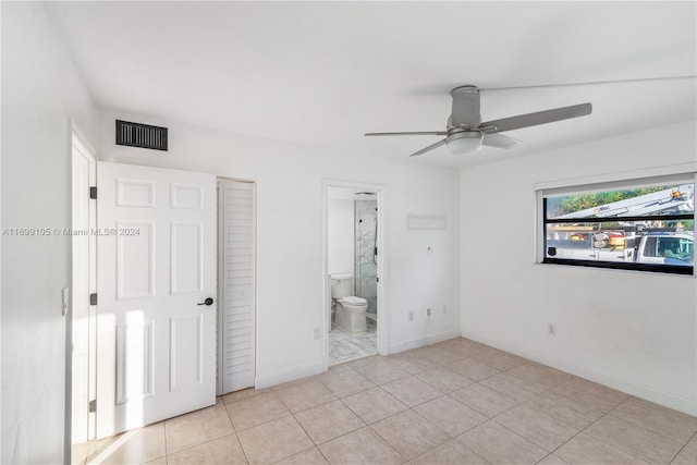 unfurnished bedroom with light tile patterned floors, ensuite bathroom, and ceiling fan