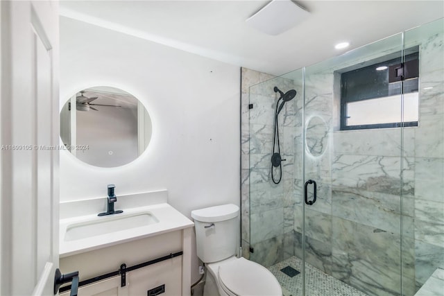 bathroom featuring vanity, toilet, ceiling fan, and a shower with shower door