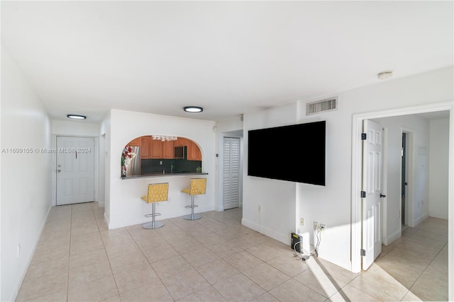 unfurnished living room featuring sink and light tile patterned flooring