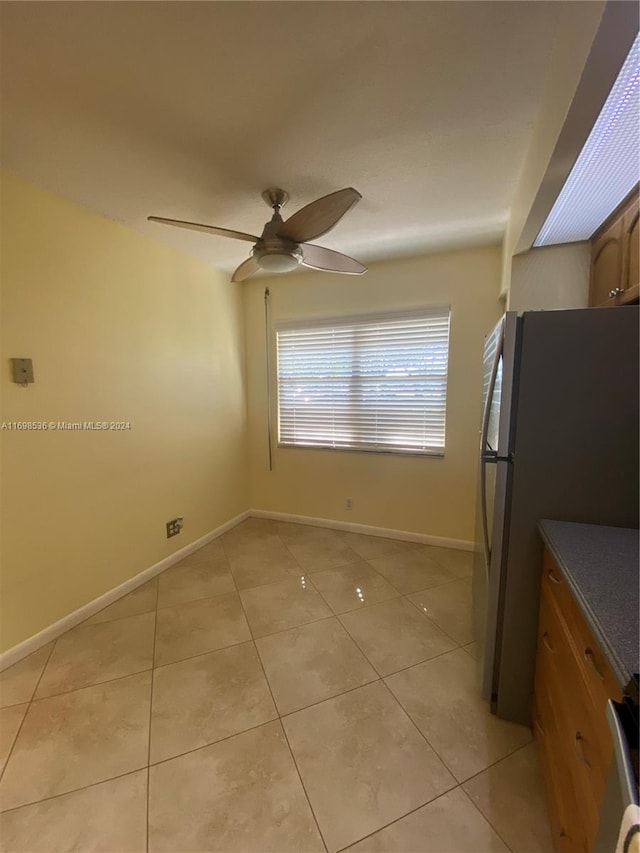 kitchen with ceiling fan, light tile patterned flooring, range, and stainless steel refrigerator