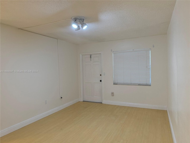 unfurnished room featuring light hardwood / wood-style floors and a textured ceiling