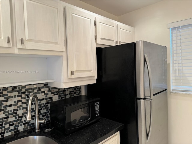 kitchen with tasteful backsplash, stainless steel refrigerator, and sink