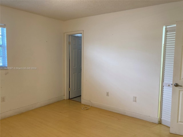 unfurnished room with light hardwood / wood-style flooring and a textured ceiling