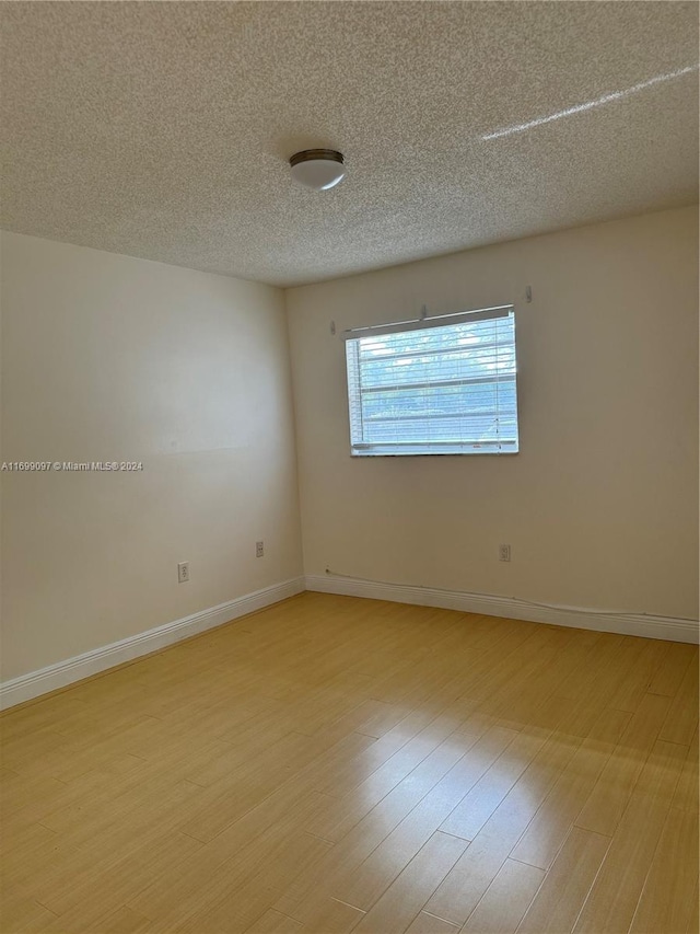 empty room featuring a textured ceiling and light wood-type flooring