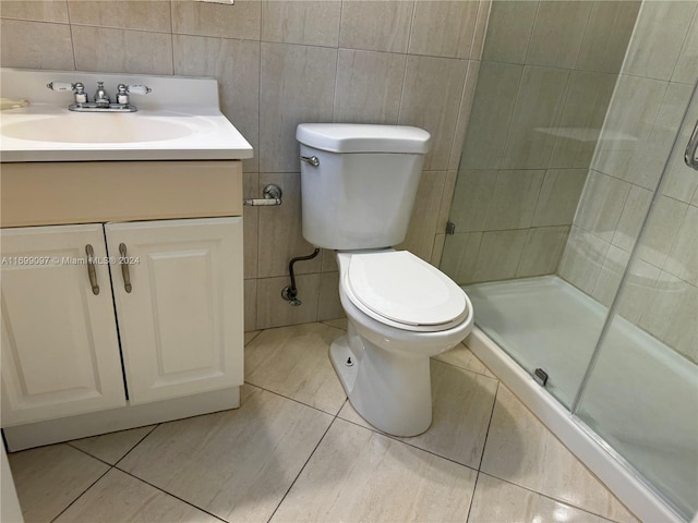 bathroom featuring vanity, tile patterned floors, toilet, tile walls, and an enclosed shower