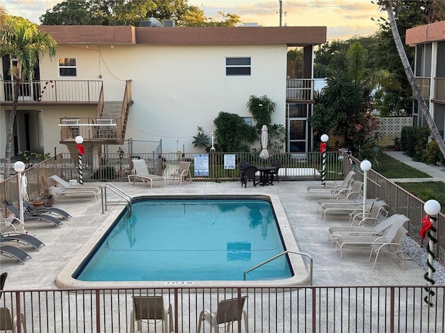 pool at dusk with a patio area