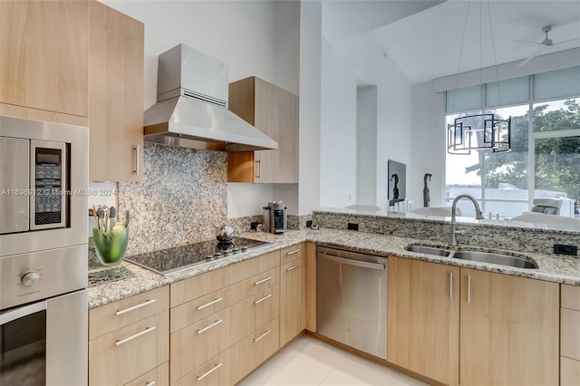 kitchen with light brown cabinets, wall chimney range hood, sink, light stone countertops, and stainless steel appliances