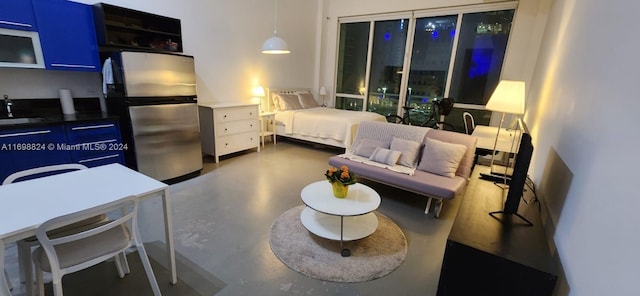 bedroom with stainless steel fridge, sink, and concrete floors