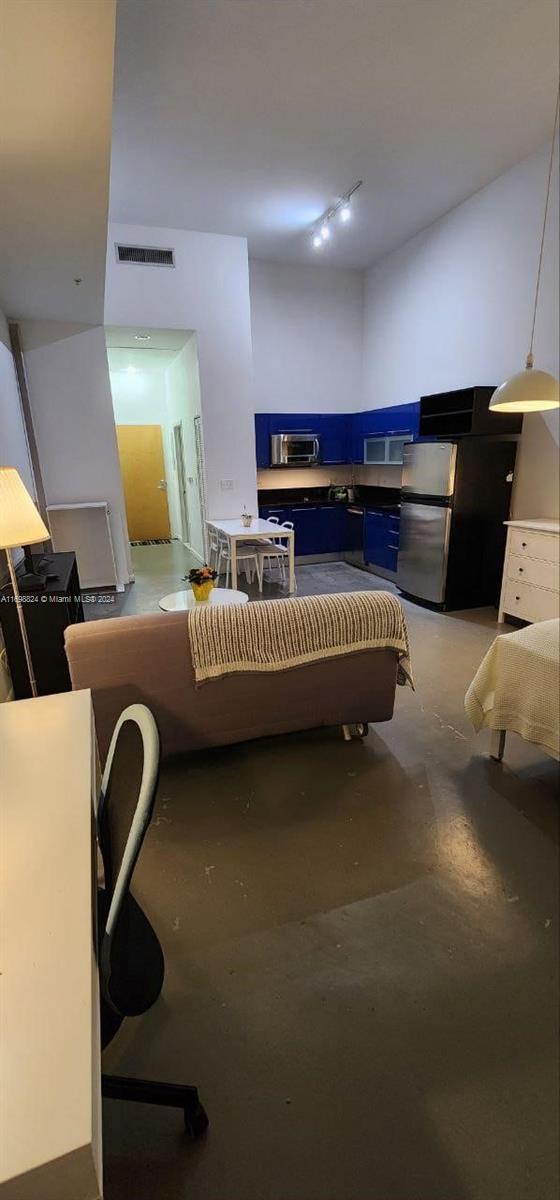 bedroom featuring stainless steel refrigerator and concrete flooring